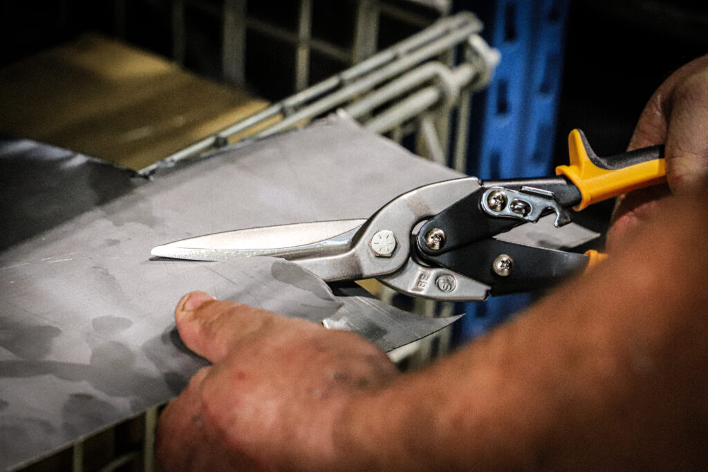 Yellow handle straight cut aviation snips cutting through sheet metal