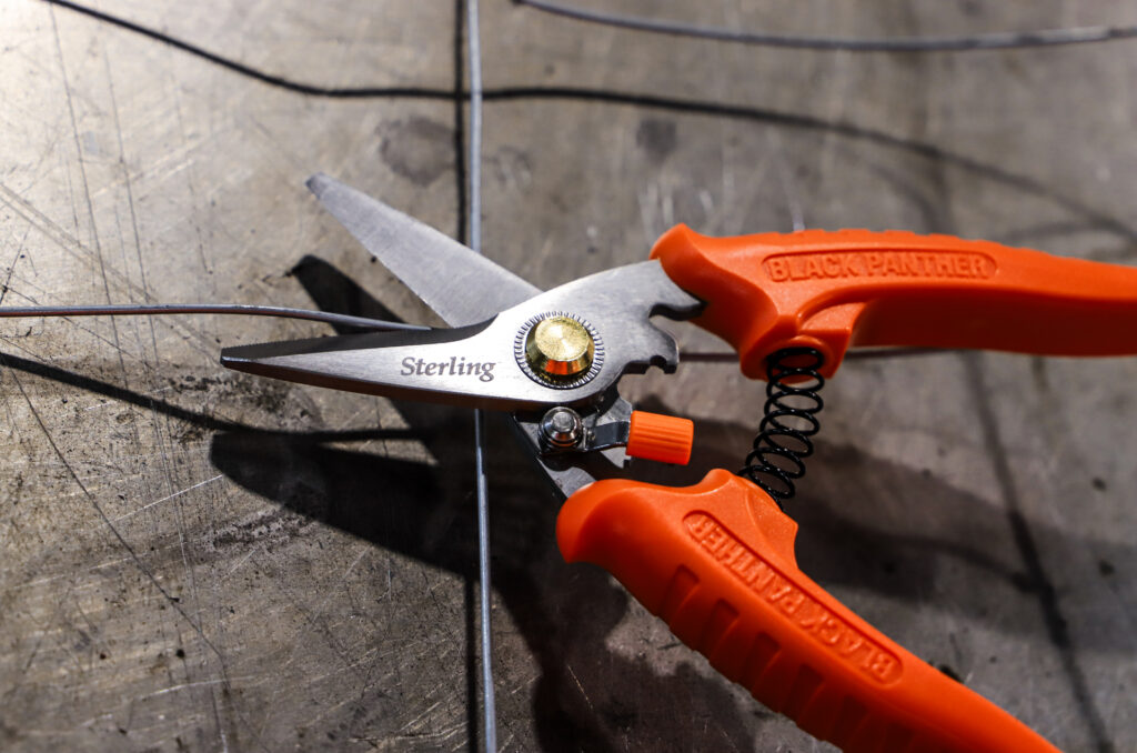 Orange handle industrial snips cutting metal wire