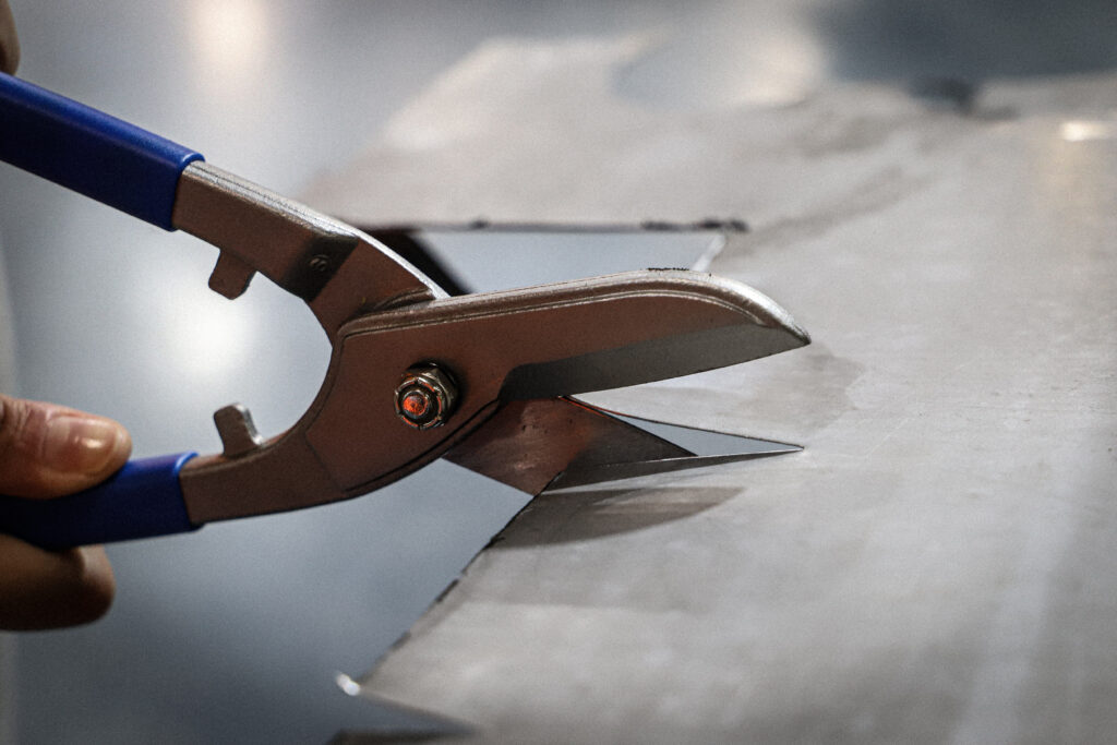 Blue handled tin snips (gilbow snips) cutting through sheet metal